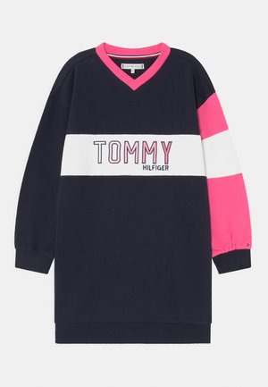 Długa, granatowa sukienka z długim rękawem, z białymi i różowymi poziomymi paskami, różowym dekoltem w kształcie litery V oraz napisem "TOMMY HILFIGER" z przodu.
