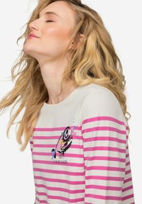 Camicia a maniche lunghe a righe in crema e rosa, con stampa grafica sul petto. Tessuto morbido con un fit rilassato e leggero scollo a barca.