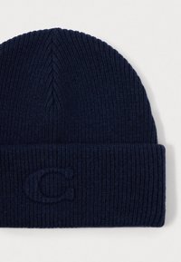 Navy knit beanie featuring a folded cuff and subtle embossed logo, made from a soft, textured wool blend. Classic, snug fit.