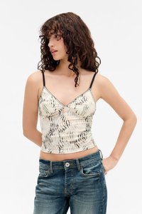 Top corto in crema con stampa zebratta nera, con spalline sottili nere e una silhouette aderente. Texture liscia e leggero lucido.