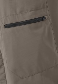 Poche en tissu beige avec une fermeture éclair noire horizontale, coutures surpiquées et un motif texturé subtil sur le matériau.