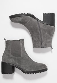 Botas de tobillo de ante gris con punta redonda, paneles laterales elásticos y cierre de cremallera. Cuentan con un tacón grueso y texturizado y suela de goma.