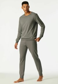 Grijze loungewear set met een lange mouw top met een ruitpatroon en bijpassende taps toelopende broek, beiden met ribgebreide boorden. Zachte stofafwerking.