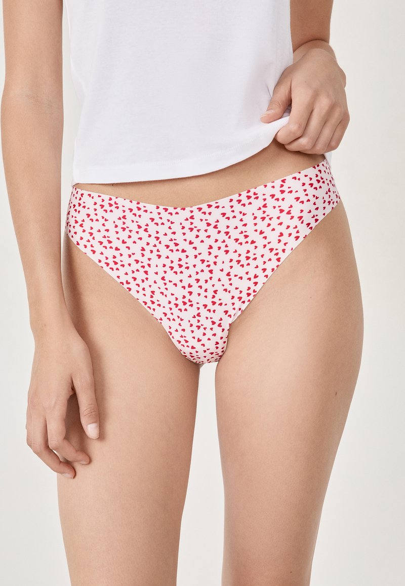 Motivo a cuori rossi su tessuto bianco, stile bikini a vita bassa, materiale morbido e elasticizzato, bordi senza cuciture e design minimalista per una copertura ridotta.