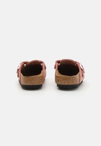 Sandali rosa con tomaia morbida, midsole in sughero e suola in gomma. Presentano cinturini regolabili e un design aperto sul retro.