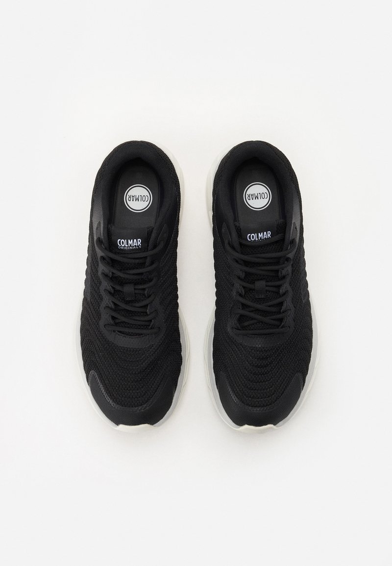 Schwarze Sportschuhe mit einem strukturierten Strick-Obermaterial, Schnürdesign und einer leicht grauen Gummisohle. Mit Logo auf der Zunge.