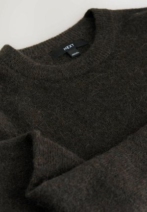 Maglione a maglia marrone realizzato in materiale morbido con scollo rotondo, dotato di una texture leggermente pelosa e fibre visibili. Etichetta del marchio esposta.