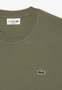 T-shirt Lacoste classica di colore verde oliva con scollo rotondo e piccolo logo coccodrillo ricamato verde sul fronte.