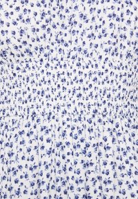 Bílá tkanina s malým modrým květinovým potiskem, s nařasením pro texturu a elastickým pasem pro tvar.