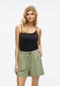 Haut sans manches noir associé à un short olive texturé avec une taille élastique et un lien à l'avant.