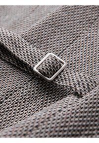 Gros plan d'une ceinture en tissu texturé avec une boucle carrée argentée dans un motif tissé noir, blanc et beige.