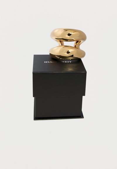 Glänzender goldener, massiver Ring, der auf einer schwarzen Box mit der Marke Hugo Kreit vor einem schlichten weißen Hintergrund liegt.