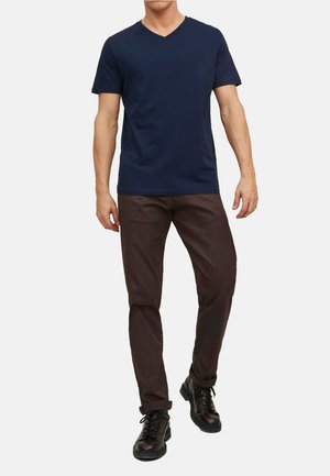 Marineblå v-hals t-shirt kombineret med brune slim-fit bukser og sorte snørebåndsstøvler. T-shirten har korte ærmer, glat tekstur og et afslappet design.