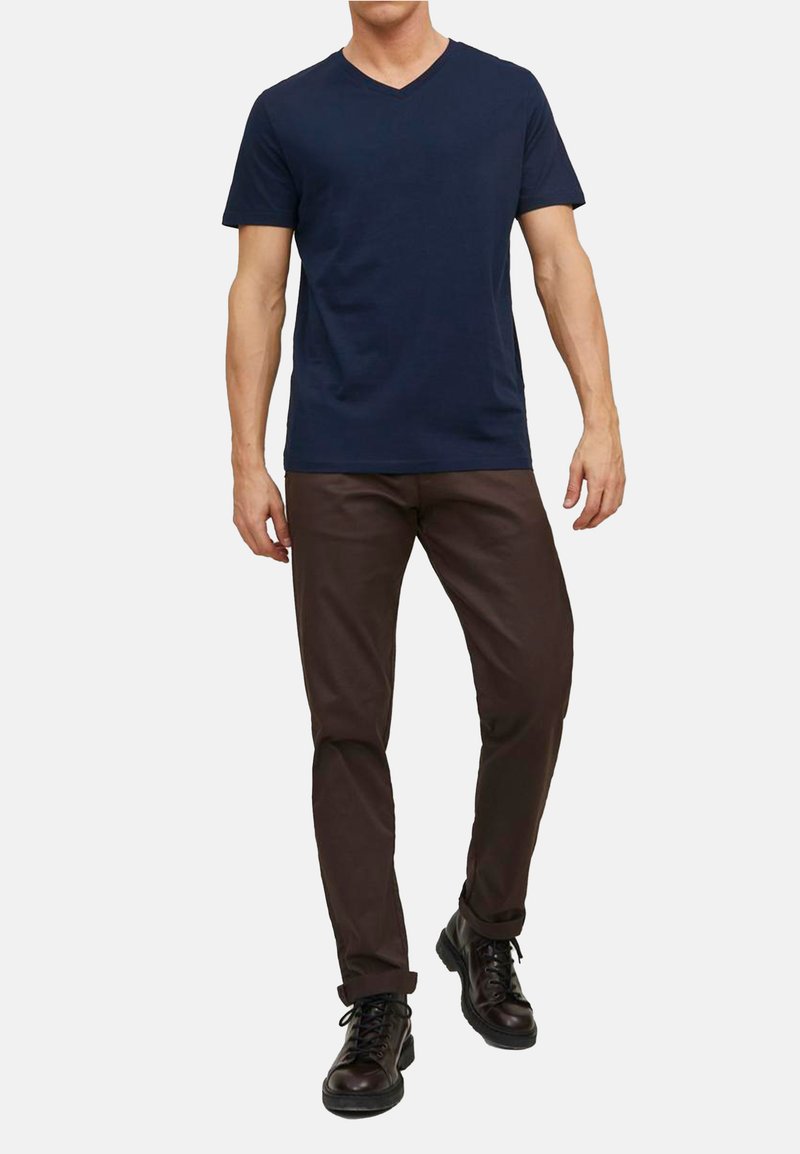 Granatowy t-shirt z dekoltem w kształcie V w połączeniu z brązowymi spodniami slim-fit i czarnymi sznurowanymi butami. T-shirt ma krótkie rękawy, gładką fakturę i casualowy design.