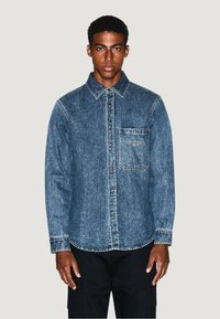 Camicia in denim, lavaggio medio, stile button-up, colletto puntato, tasca sul petto singola, cuciture in vista, maniche lunghe, vestibilità comoda.