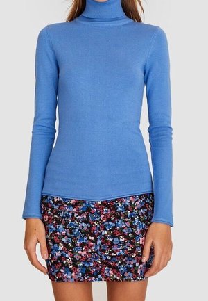 Blauwe coltrui van een zachte gebreide stof, gecombineerd met een minirok met bloemenpatroon en veelkleurige bloemen op een donkere achtergrond.