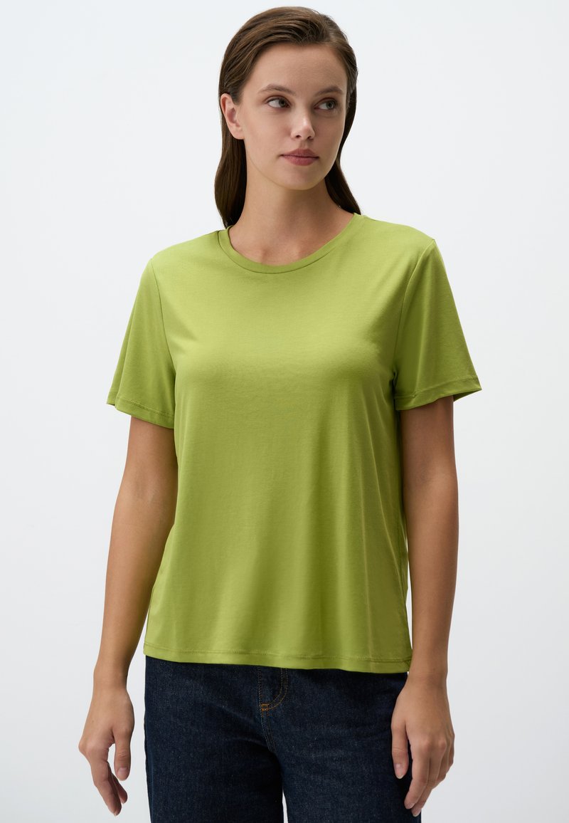 T-shirt verde in cotone con scollatura rotonda e maniche corte; vestibilità rilassata con una consistenza liscia e senza pattern o decorazioni visibili.