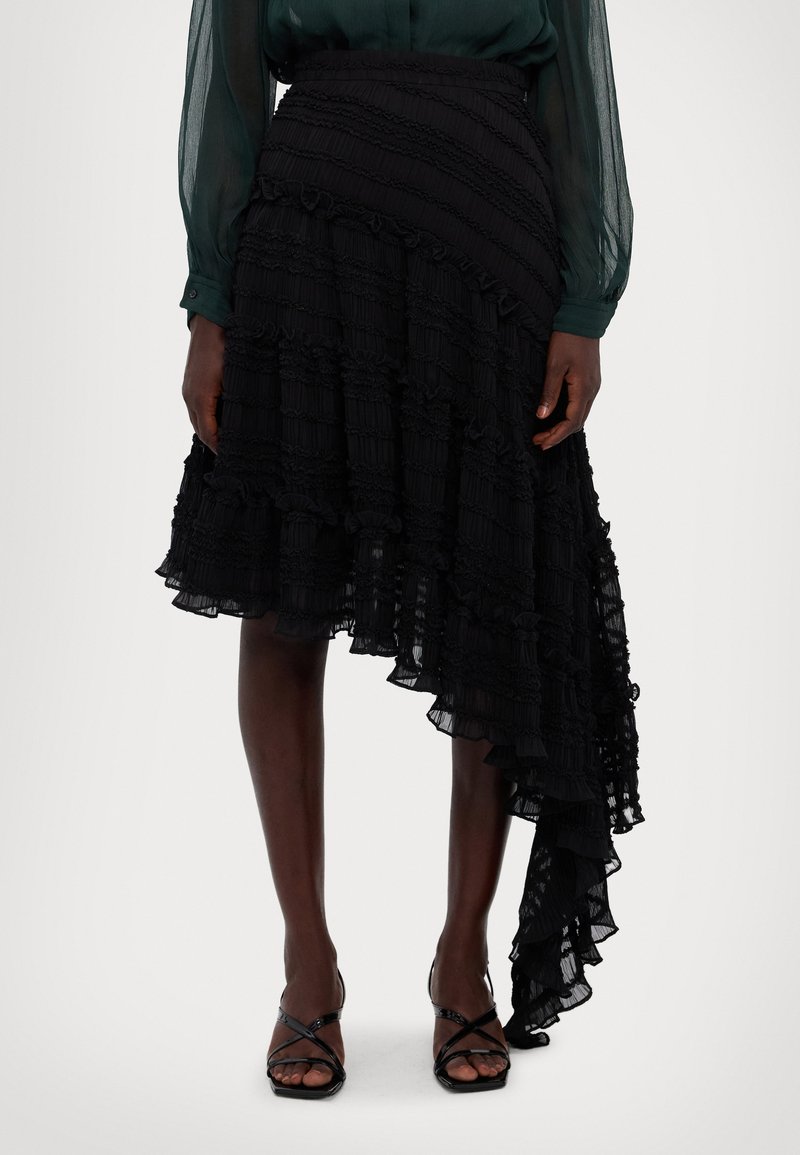 Zwarte asymmetrische rok met ruffles van gelaagd stof met textured strepen. Kenmerkt zich door een aansluitende taille en een vloeiende onderkant met franje.