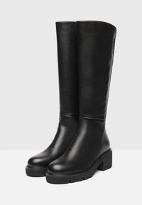 Botas negras hasta la rodilla con un acabado de cuero suave, tacones de bloque y una suela texturizada. Presentan un diseño limpio sin hardware visible.