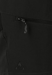 Svart tygjacka med en ficka med dragkedja, texturerad sömnad och en broderad logotyp i det nedre hörnet.