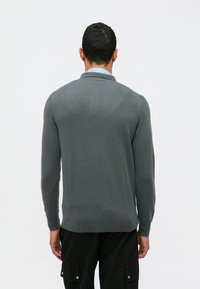 Gray long-sleeve sweater with a textured knit, featuring a folded collar and ribbed trim at the cuffs and hem. Casual fit.