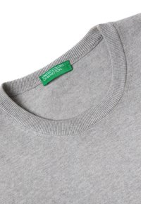 Grå crewneck-tröja i mjukt tyg. Har ribbad halsringning och en igenkännbar grön etikett med texten "United Colors of Benetton".