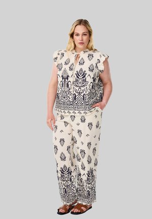 Two-piece outfit featuring a cream top and pants with navy blue geometric patterns; top has ruffled sleeves and a keyhole neckline.