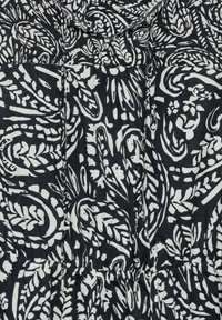 Prenda de diseño en blanco y negro con un patrón floral, cintura fruncida y cierre con lazo. Confeccionada en tejido ligero y de suave textura.
