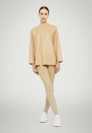 Beige synthetisch top met driekwartmouwen, gecombineerd met lichtgouden, glinsterende leggings en witte sportschoenen. Vlekkeloze texturen, minimalistisch ontwerp.