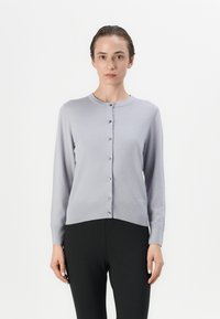 Cardigan malha lilás claro com decote redondo e mangas longas, apresentando uma frente com botões e uma textura suave. Os acabamentos incluem botões prateados.