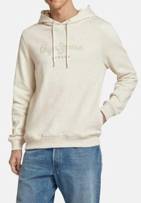 Sudadera de color crema hecha de tela suave, con capucha ajustable, puños de canalé y el logo grabado "Pepe Jeans London" en la parte delantera.