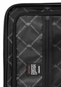 L'intérieur de la valise noire est doté d'une doublure en nylon avec un motif en répétition du logo "WITTCHEN", des poches en filet zippées et une étiquette contenant des instructions d'entretien.