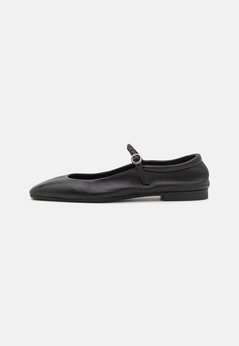 Black leather ballet flats with a rounded toe, narrow vamp, and a small ankle strap featuring a circular buckle. Low, flat sole.