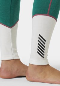 Groene leggings met witte enkelstukken en bordeauxkleurige stiksels. Bevat een zwart gestreept logo detail op het onderbeen. Rekbare stof.