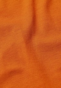 Stickad tyg i en livlig orange nyans. Har en slät textur med en subtil sträckning och jämn ribbning genom hela tyget.