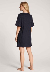 Navy blue nightdress with white polka dots, short ruffled sleeves, and a relaxed fit, designed with a rounded neckline and a knee-length cut.