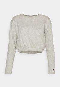 Ljusgrå långärmad kort sweatshirt med elastiskt midjeband och liten Champion-logotyp på vänster ärmslut.