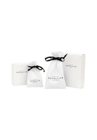 Trois sacs blancs avec des liens noirs et du texte, et une boîte blanche avec du texte noir. Les sacs sont de tailles différentes, tous fabriqués à partir d'un matériau doux.