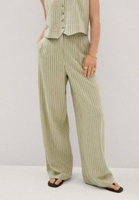 Jasnozielony, pionowo paskowany dwuczęściowy strój z bezrękawą bluzką na guziki i szerokimi spodniami. Miękka tkanina, luźny krój.