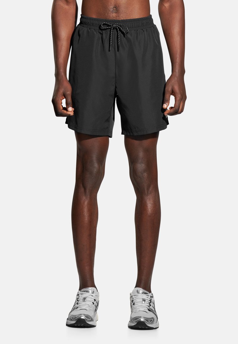 Czarne sportowe spodenki z elastycznym pasem, ze sznurkiem i bocznymi kieszeniami. Lekki materiał o gładkiej teksturze, o długości do kolan.