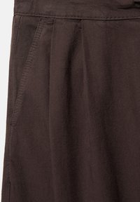 Gros plan sur un pantalon marron foncé avec poche latérale visible, plis et détails de couture dans un tissu doux et texturé.