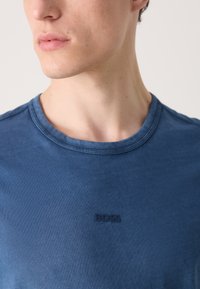 T-shirt κοντομάνικο με στρογγυλή λαιμόκοψη από υφασμάτινο μπλε υλικό, που διαθέτει διακριτό ανάγλυφο λογότυπο "BOSS" στο στήθος.