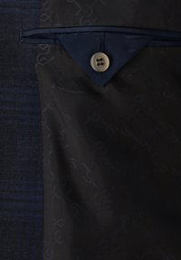 Marineblau gemusterte Stoffjacke mit einer strukturierten Karoseite, ausgestattet mit einer kontrastierenden blauen Taschenklappe und einem runden Knopf.