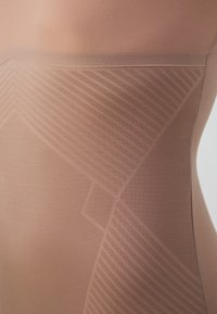 Permatomas, kūno spalvos bodis su lygia tekstūra ir geometriniu raštu. Savybės: be siūlų viršus ir subtilus linijų dizainas ant audinio.