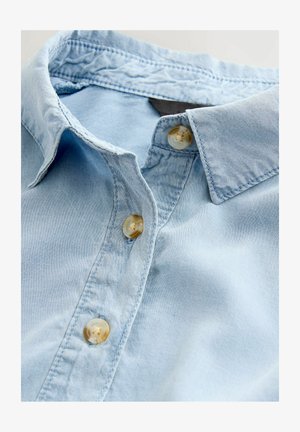 Lichtblauw denim overhemd met een klassieke kraag, voorzien van beige knopen en een zachte textuur. Close-upweergave met focus op de kraag en knopen.