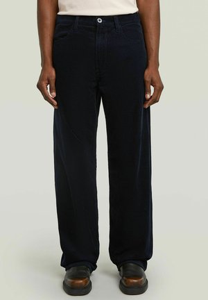Pantaloni in corduroy blu navy con una vestibilità a gamba larga, dotati di tasche frontali, chiusura con bottone e coste testurizzate in tutto il tessuto.