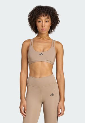 Tan sportbeha en high-waisted leggings, gemaakt van een gladde stof, met dunne bandjes en zwarte logo-accenten. Eenvoudig, getailleerd ontwerp.
