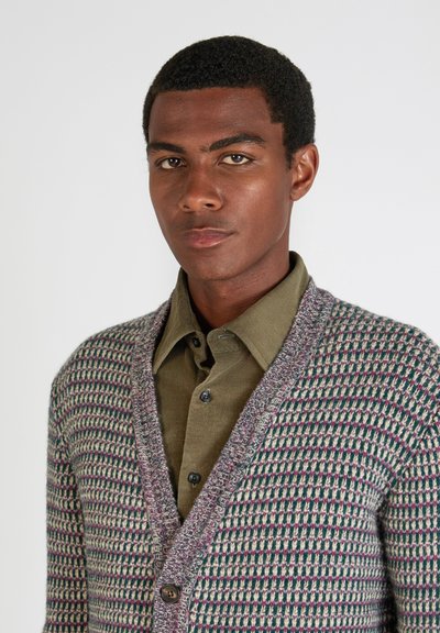 Sweter z dzianiny z wzorem w pied mesh w odcieniach beżu, zieleni i różu. Posiada kołnierz szalowy i dwa guziki z przodu.