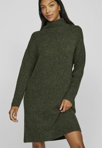 Abito a collo alto lavorato a maglia in verde oliva scuro, con maniche lunghe, vestibilità rilassata, orlo a coste e texture morbida.