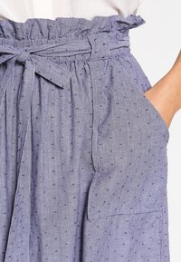 Sininen ja valkoinen raidoitettu hame, jossa on rypytetty vyötärö, kangashihna, kaksi sivutaskua ja hienovaraiset teksturoidut pisteet materiaalissa.